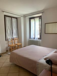 a bedroom with a bed and two chairs and windows at Appartamenti Sole e Lago in Gravedona