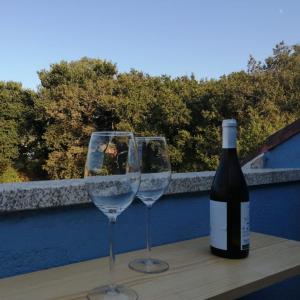 una botella de vino y dos copas de vino en una mesa en Ático O Rial, en Puentecesures