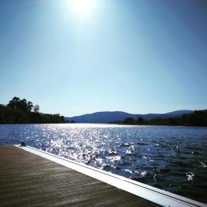 un molo su un lago con il sole che riflette sull'acqua di Ático O Rial a Puentecesures