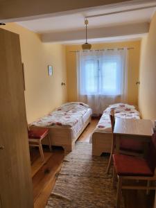 a room with two beds and a table and a window at Białowieża 131 in Białowieża