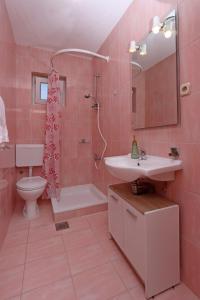 a pink bathroom with a sink and a toilet at Apartments by the sea Barbat, Rab - 14247 in Rab