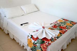 een wit bed met een bloemendeken erop bij Comodas Habitaciones Hotel Bucaros in Espinal