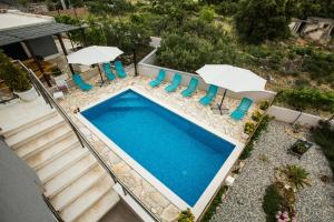 an overhead view of a swimming pool with chairs and umbrellas at Family friendly house with a swimming pool Dvornica, Rogoznica - 14300 in Rogoznica