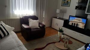 Apartments with a parking space Tugare, Omis - 14320 في Tugare: غرفة معيشة فيها كرسي وتلفزيون