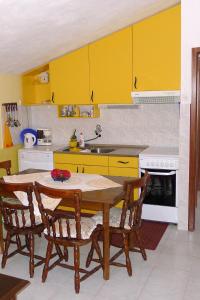 une cuisine avec des armoires jaunes, une table et des chaises dans l'établissement Apartments by the sea Sevid, Trogir - 14337, à Marina