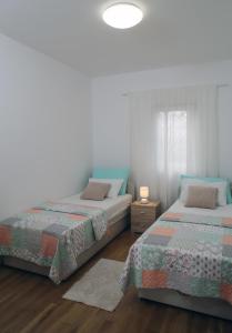 two beds sitting next to each other in a bedroom at Apartments by the sea Razanj, Rogoznica - 14357 in Rogoznica