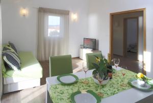 ein Wohnzimmer mit einem Tisch und grünen Stühlen in der Unterkunft Apartments by the sea Razanj, Rogoznica - 14357 in Rogoznica