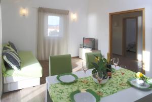 a living room with a table and green chairs at Apartments by the sea Razanj, Rogoznica - 14357 in Rogoznica