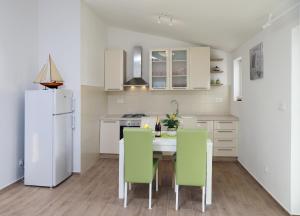 eine Küche mit einem Tisch und Stühlen sowie einem Kühlschrank in der Unterkunft Apartments by the sea Razanj, Rogoznica - 14357 in Rogoznica