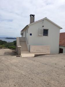 a white house with stairs leading up to it at Apartments with a parking space Savar, Dugi otok - 14373 in Savar