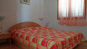 1 dormitorio con 1 cama con edredón rojo y amarillo en Apartments by the sea Prizba, Korcula - 14385, en Prizba