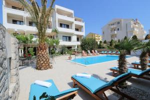 ノヴァリャにあるFamily friendly apartments with a swimming pool Novalja, Pag - 14394のスイミングプール、青いラウンジチェアが備わるリゾートです。
