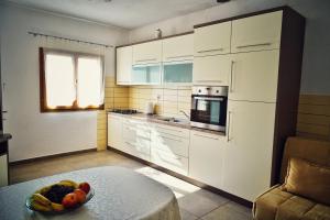 a kitchen with white cabinets and a bowl of fruit on a table at Apartments by the sea Povlja, Brac - 14399 in Povlja