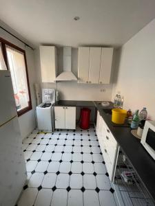 a kitchen with white cabinets and a black and white tiled floor at Agréable appartement dans une maison in Saint-Denis