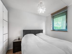 een witte slaapkamer met een bed en een raam bij Modern holiday home in Lochem with private garden in Lochem