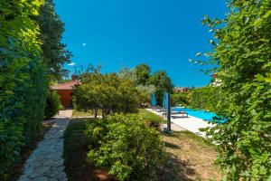 a garden with a pool and trees and a building at Family friendly house with a swimming pool Sveti Lovrec, Central Istria - Sredisnja Istra - 14432 in Sveti Lovreč Pazenatički