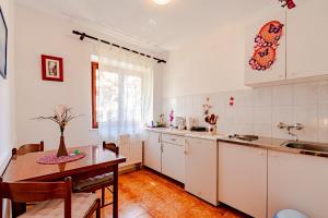 cocina con armarios blancos, mesa y fregadero en Apartments and rooms with parking space Mali Ston (Peljesac) - 14434, en Mali Ston