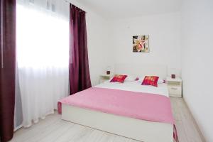 biała sypialnia z dużym łóżkiem z różową pościelą w obiekcie Apartments with a parking space Bibinje, Zadar - 14436 w Bibinje