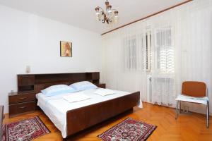 1 dormitorio con 1 cama grande y 1 silla en Apartments by the sea Sumpetar, Omis - 14450 en Jesenice