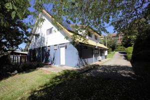 a white house with a driveway next to a yard at Blizzard Bunny Lodge 43 Gippsland Street in Jindabyne