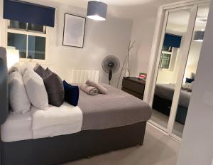 a bedroom with a bed with pillows and a mirror at Super Luxe Central Maidenhead Apartment in Maidenhead