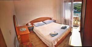 ein Schlafzimmer mit einem Bett mit blauen Kissen und einem Fenster in der Unterkunft Apartment Povlja 14399c in Povlja