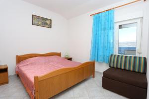 a bedroom with a bed and a window and a chair at Apartments by the sea Slatine, Ciovo - 14541 in Slatine
