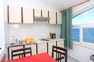 a kitchen with a red table and chairs and a window at Apartments by the sea Slatine, Ciovo - 14541 in Slatine