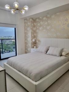 Un dormitorio blanco con una cama grande y una ventana en DOWNTOWN DORAL, FLORIDA. NEW CONDO STYLE RESORT. en Miami
