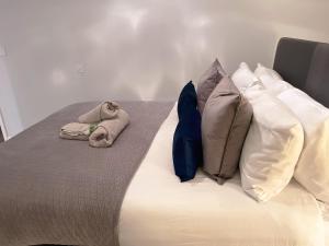 Una cama con tres almohadas y dos animales de peluche. en Super Luxe Central Maidenhead Apartment en Maidenhead