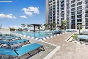 une piscine avec des chaises bleues et un bâtiment dans l'établissement DOWNTOWN DORAL, FLORIDA. NEW CONDO STYLE RESORT., à Miami