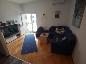 a living room with a blue couch and a television at Apartments by the sea Marina, Trogir - 14191 in Marina