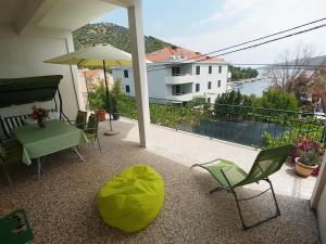 a balcony with a green chair and an umbrella at Apartments by the sea Marina, Trogir - 14191 in Marina