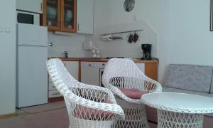 kuchnia z białymi wiklinowymi krzesłami i stołem w obiekcie Apartments with a parking space Poljica, Trogir - 16299 w Marinie