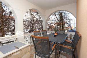 a table and chairs on a balcony with two arched windows at Apartments by the sea Slatine, Ciovo - 16341 in Slatine