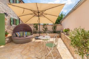 een patio met een parasol en een tafel en stoelen bij Family friendly house with a swimming pool Cerion, Central Istria - Sredisnja Istra - 16332 in Višnjan