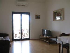 a living room with a tv and a door to a patio at Apartment Palit 16356b in Mundanije