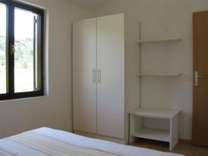 a bedroom with white cabinets and a bed and a window at Apartment Palit 16356b in Mundanije