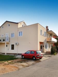 czerwony samochód zaparkowany przed budynkiem w obiekcie Apartments with a parking space Umag - 16354 w mieście Umag