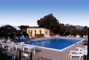 una piscina con sillas blancas y un edificio en Agriturismo Villa Caprareccia, en Bibbona