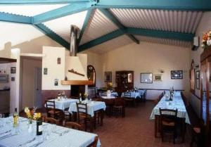a restaurant with white tables and chairs and blue ceilings at Agriturismo Villa Caprareccia in Bibbona