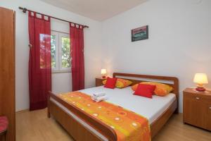 Schlafzimmer mit einem Bett mit roten und orangefarbenen Kissen in der Unterkunft Holiday house with a swimming pool Rogac, Solta - 16444 in Grohote