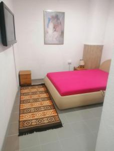 a bedroom with a large bed with pink sheets and a rug at Sphinx Apartment in Visoko