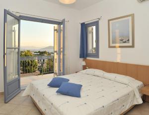 um quarto com uma cama grande e uma varanda em Fistikies Holiday Apartments em Aegina Town