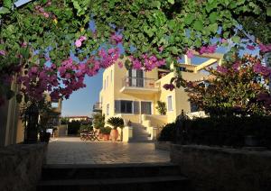 Um edifício com flores cor-de-rosa à frente. em Fistikies Holiday Apartments em Aegina Town