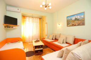 ein Wohnzimmer mit orangefarbenen und weißen Möbeln und einem TV in der Unterkunft Apartments by the sea Podgora, Makarska - 16476 in Podgora