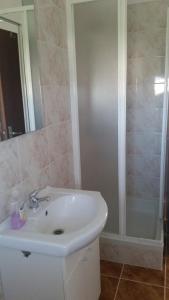 La salle de bains est pourvue d'un lavabo blanc et d'une douche. dans l'établissement Apartments with a parking space Kolan, Pag - 16482, à Kolan
