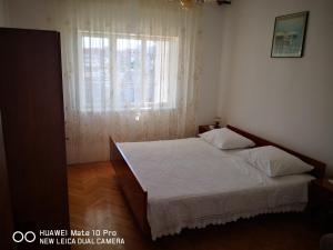Un dormitorio con una cama grande y una ventana en Apartments with a parking space Seget Vranjica, Trogir - 14212, en Seget Vranjica