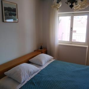 1 dormitorio con 1 cama con 2 almohadas y ventana en Apartments with a parking space Seget Vranjica, Trogir - 14212, en Seget Vranjica