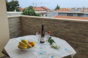 羅維尼的住宿－Apartments with a parking space Rovinj - 16498，一张桌子,上面放着一碗水果和一瓶葡萄酒